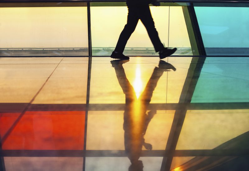Low angle view of person walking through back lit corridor